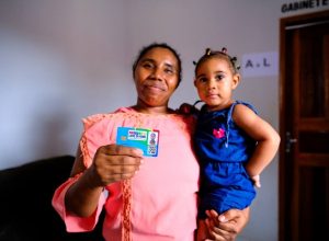 Mulher com crianca no colo mostra cartao do programa Maranhao Livre da Fome